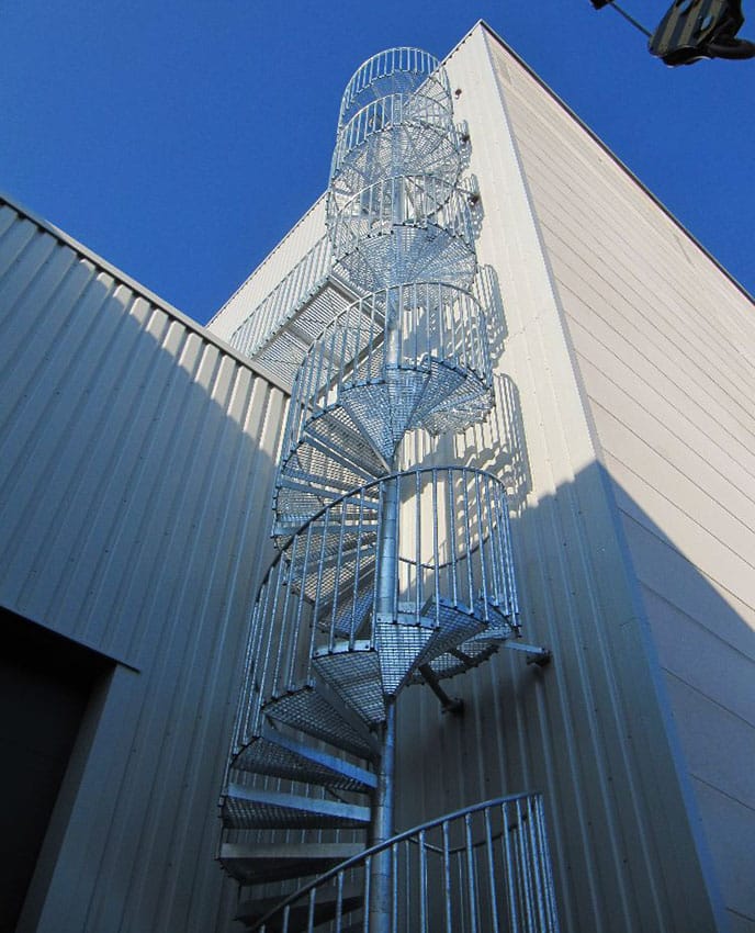 Feuerverzinkte Spindeltreppe außen an einer Industriehalle, Blick von unten nach oben.